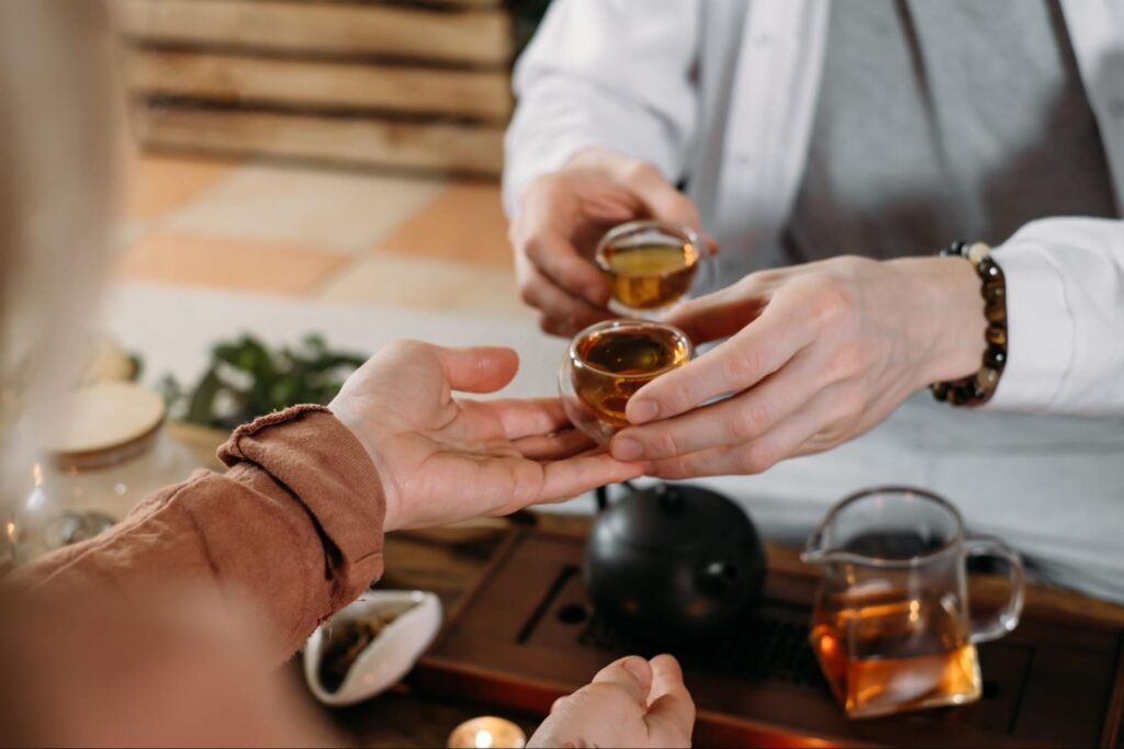 A herbalist hands a patient a cup of herbal tea, offering natural healing and wellness support through herbal remedies.