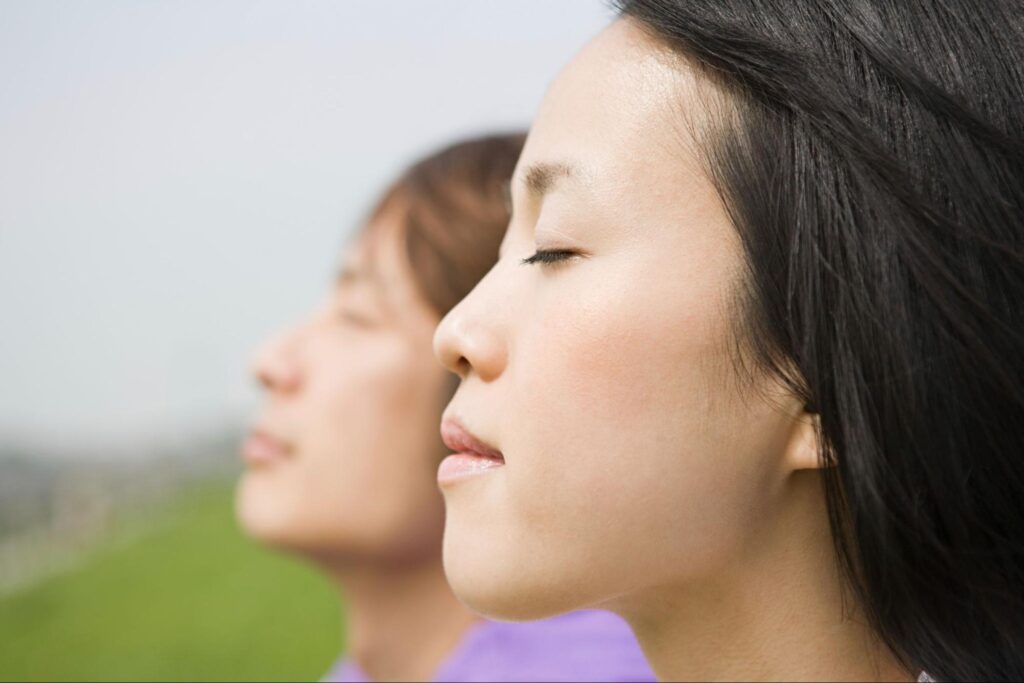 A close-up shot of two people practicing mindfulness meditation outdoors, enjoying a peaceful moment.