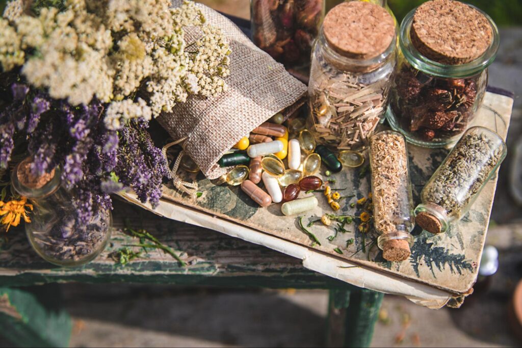 Various dried medicinal herbs are stored in jars and vials, with different capsules on the table.